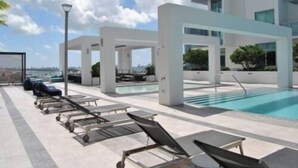 A rooftop pool area with lounge chairs and a clear view of the city skyline. - Luxury 1 Bedroom Condo with Free Parking (Miami)