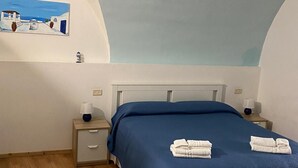 Ein Schlafzimmer mit Bett, Nachttischen, einem Wandbild und einer Decke in hellblau.