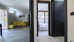 A room with a bed, a yellow sofa, and a small table. - Hostdomus - Azimut Apartment (Liguria)