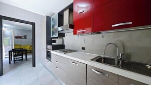 A modern kitchen with a microwave, stove, and sink. - Hostdomus - Azimut Apartment (Liguria)