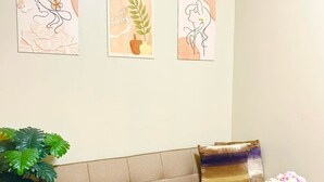A living room with a sofa, a wooden table, and three wall-mounted artworks. - Cozy 1-bedroom condo walking distance to MOA (Pasay City)