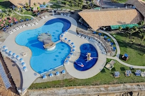 A large swimming pool with multiple lanes and a central island, surrounded by lounge chairs and umbrellas. - Makai Resort All Inclusive (Aracaju)