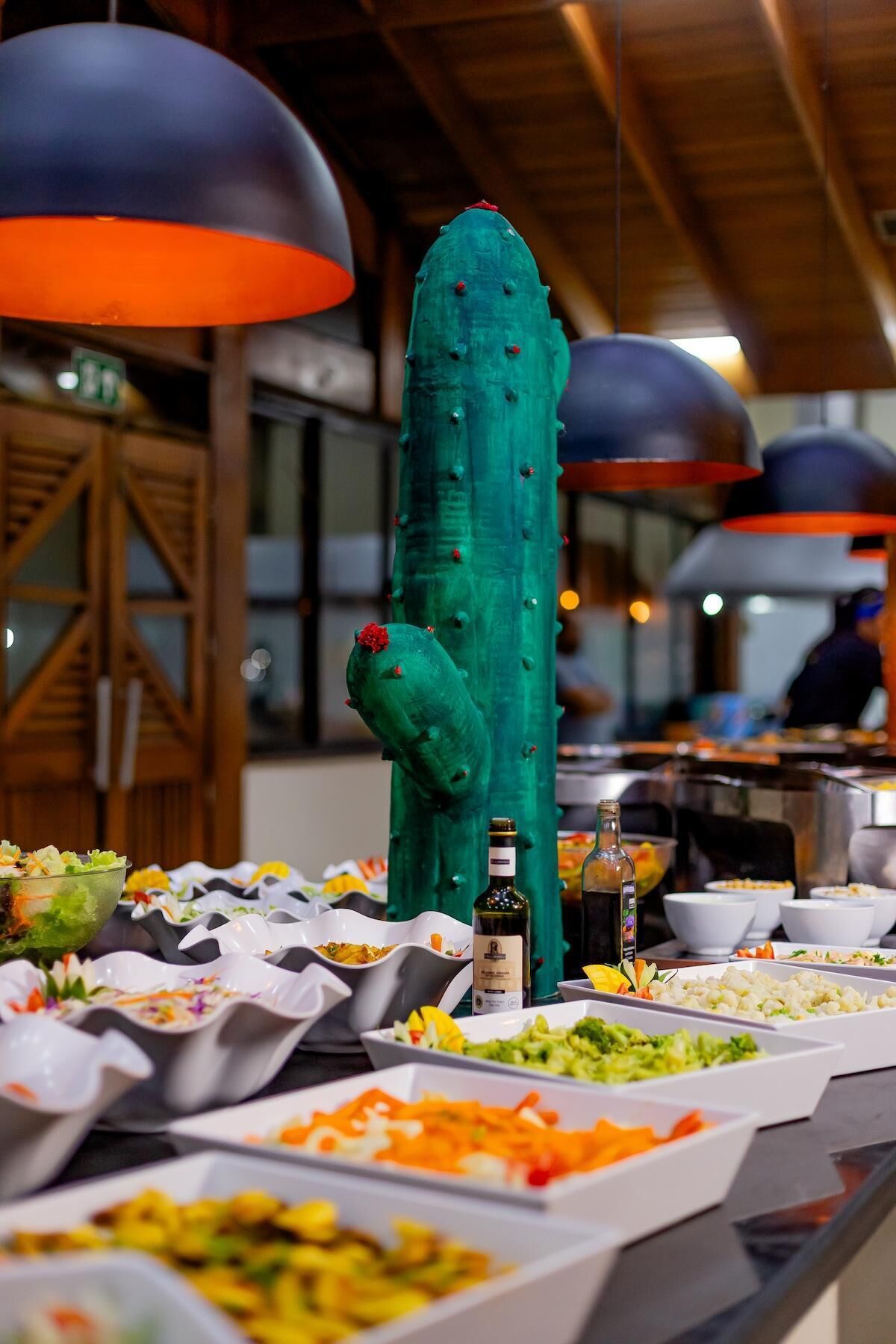 Buffet com diversos pratos e uma grande decoração de cacto.