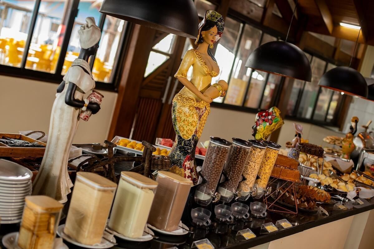Disposição de buffet com diversos alimentos e uma estátua decorativa.