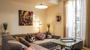 Un salon moderne avec un canapé, une table basse en verre et un tableau accroché au mur.