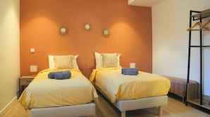 A room with two beds, a radiator, and a clothing rack.