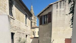 Un bain à remous doté d’un panneau de commande, entouré de bâtiments en pierre et sous un ciel dégagé.