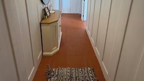 Um corredor com paredes brancas, teto de madeira e tapete estampado.