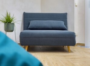 A grey sofa with wooden legs, a potted plant, and a tiled floor. - Fauda House 2, in the historic city center (Palermo)