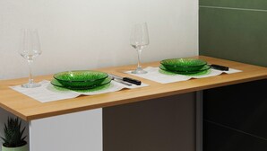 Eine Küchenarbeitsplatte mit zwei grünen Glaskästen, zwei Weingläsern und einem Messer auf einer weißen Tischmatte.