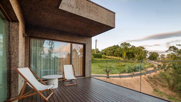 Una terraza moderna al aire libre con dos sillones reclinables y una mesita, con vistas a un jardín ajardinado.
