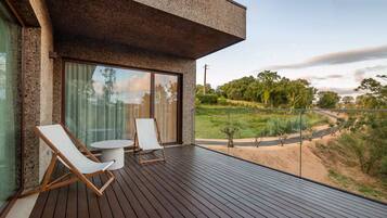 A modern outdoor deck with two lounge chairs and a small table, overlooking a landscaped garden.