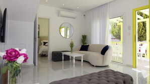 A modern living room with a sofa, a round mirror, a white coffee table, and a tufted ottoman. - Yellow 16 Sea View Vacation Home (Paphos)
