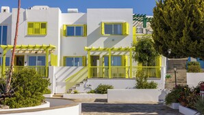 A modern building with white walls and yellow accents, featuring balconies and a staircase leading to the entrance. - Yellow 16 Sea View Vacation Home (Paphos)