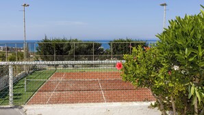A tennis court with a net, surrounded by a fence, and a view of the sea in the background. - Yellow 16 Sea View Vacation Home (Paphos)