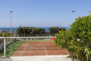 A tennis court with a net, surrounded by a fence, and a view of the sea in the background. - Yellow 16 Sea View Vacation Home (Paphos)