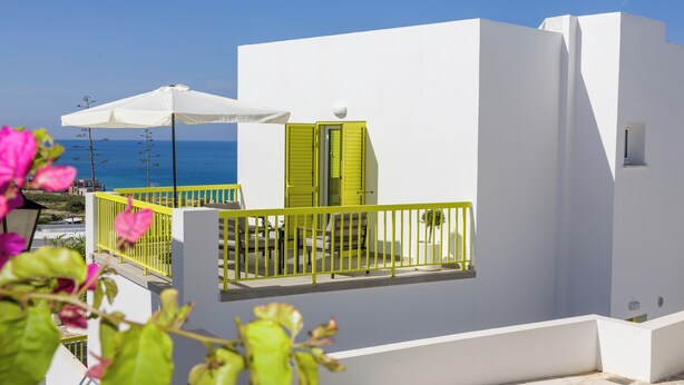 A white building with a balcony, a white umbrella, and a view of the sea. - Yellow 16 Sea View Vacation Home (Paphos)