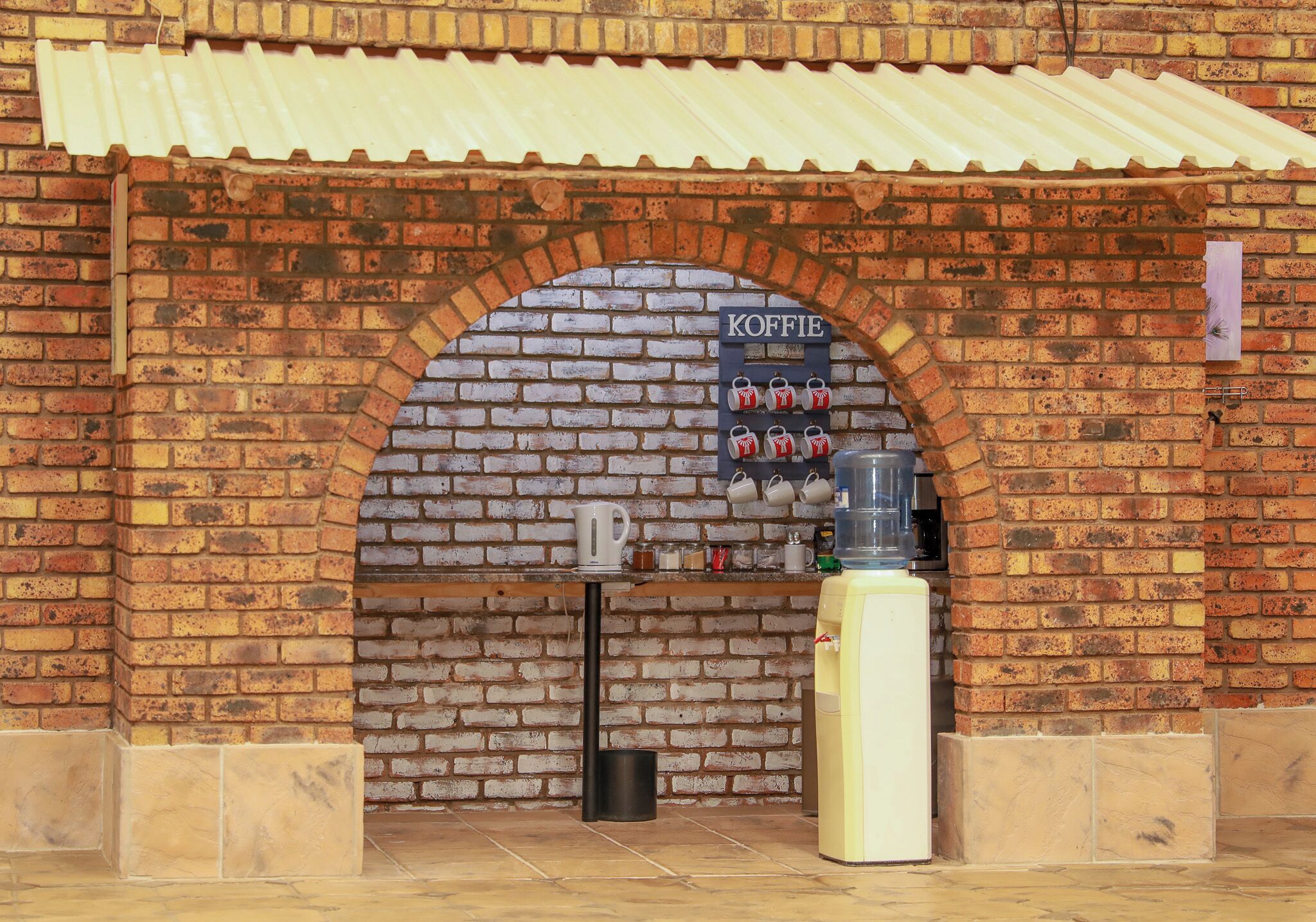 A brick wall with a KOFFIE sign and a water dispenser.