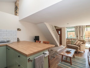 A kitchen with a wooden countertop, green cabinets, and a tiled backsplash. - Wheelwright Cottage (Moreton-in-Marsh)