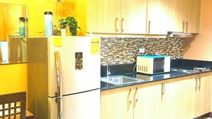 A kitchen with wooden cabinets, a refrigerator, a microwave, and a sink.