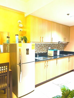 Cozinha com armários de madeira, geladeira, micro-ondas e pia.