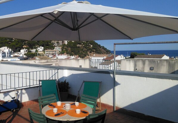 Eine Terrasse mit Tisch, Stühlen und einem großen Sonnenschirm.