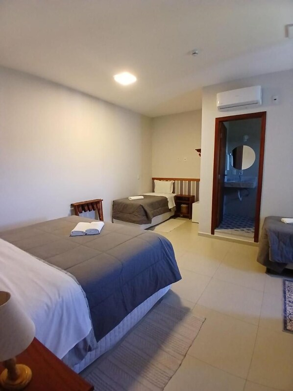 A hotel room with a bed, a chair, a desk, a mirror, and an air conditioning unit. - Vila de Cunha Inn (Cunha)