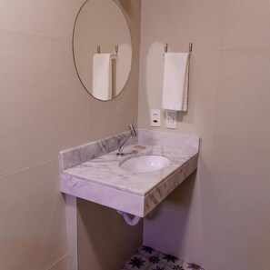 A bathroom with a marble sink, a round mirror, and a towel rack. - Vila de Cunha Inn (Cunha)