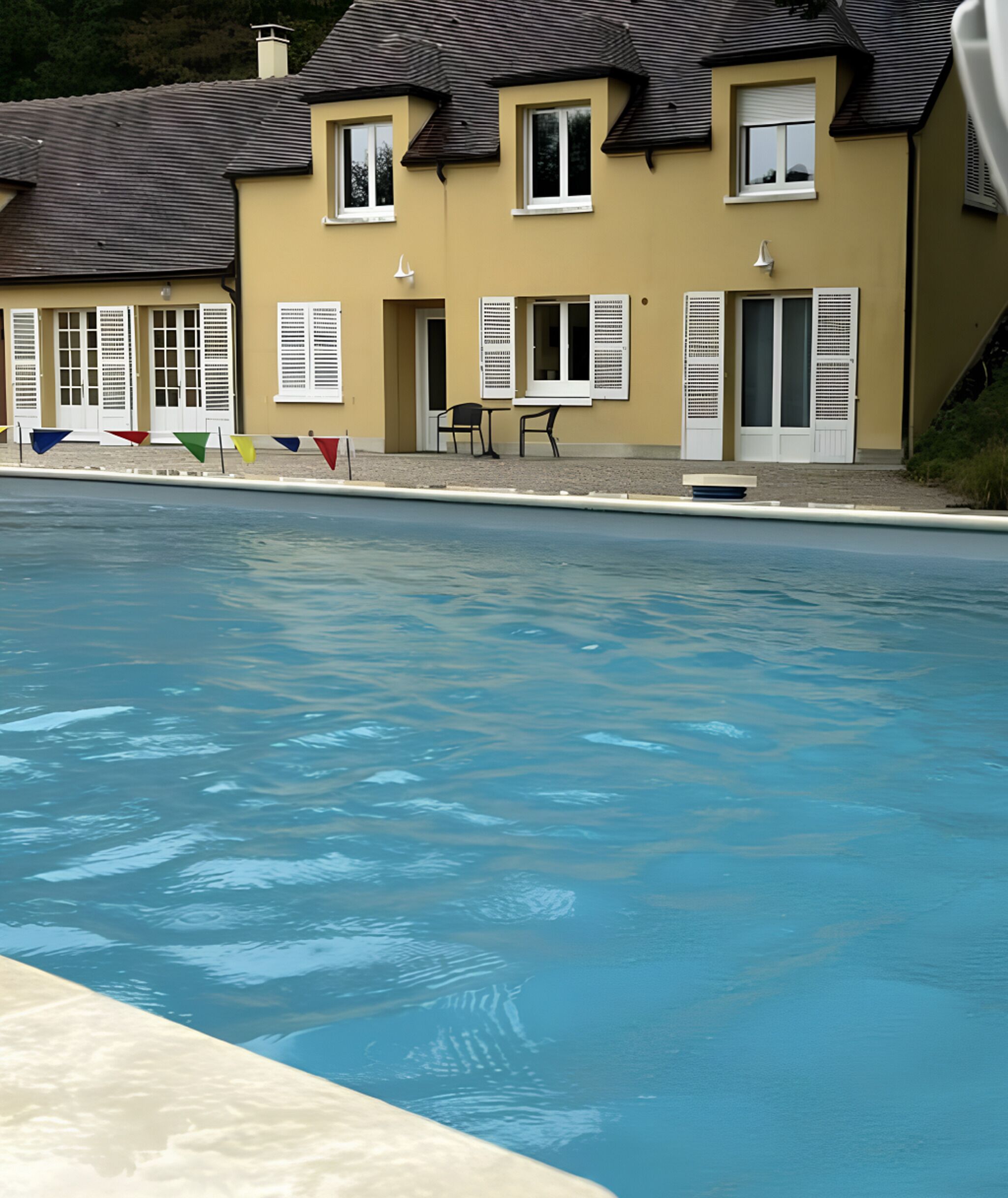 A swimming pool with a house in the background.