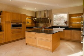 A modern kitchen with wooden cabinets, a central island, stainless steel appliances, and a window providing natural light. - Estate with a lake and recreational activities for the whole family: Vacation Rental, Manor House, and Tipis (Montigny-le-Chartif)