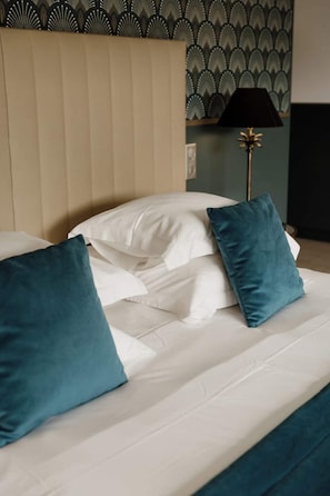A bed with white bedding and teal pillows, a headboard, and a patterned wall in the background. - Estate with a lake and recreational activities for the whole family: Vacation Rental, Manor House, and Tipis (Montigny-le-Chartif)