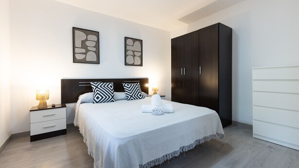 A neatly arranged bedroom with a bed, bedside tables, and a wardrobe. - DALI Apartment - Right in the city centre (Salou)