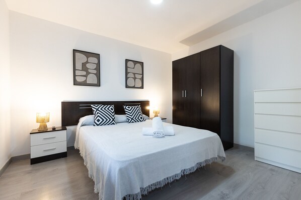 Un dormitorio ordenado con cama, mesitas de noche y un armario.