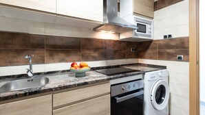 A modern kitchen with a sink, stove, microwave, and built-in oven. - DALI Apartment - Right in the city centre (Salou)