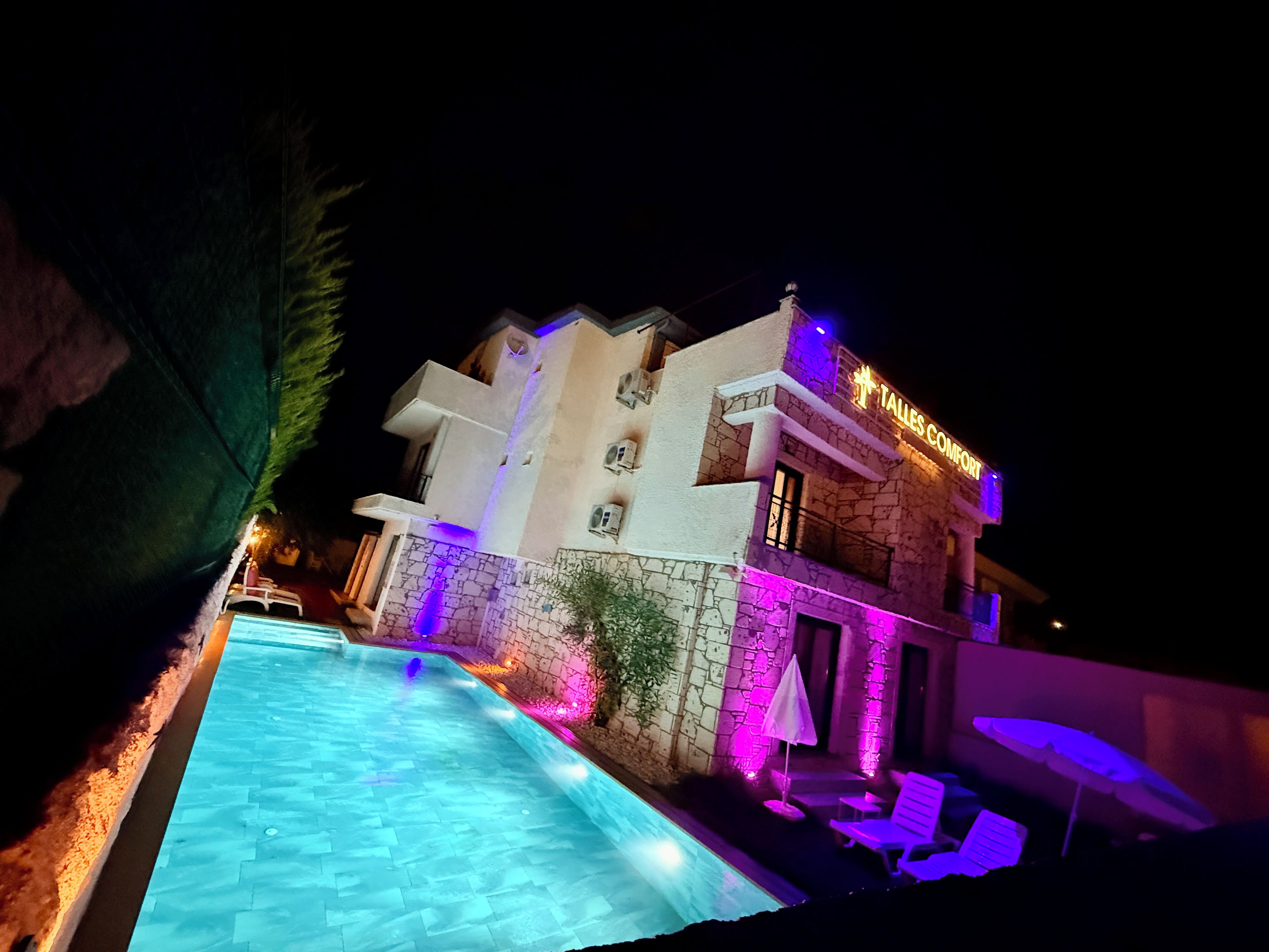 Un hotel con piscina, mobiliario exterior y fachada de piedra.