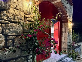 Un edificio de piedra con una puerta roja y una escalera que lleva hasta él.