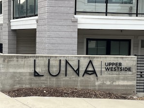 Ein Schild mit der Aufschrift 'LUNA Upper Westside', im Hintergrund ein modernes Gebäude.