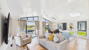 A spacious living area with a large sofa, a dining table, and a kitchen island. - Swanlake Lodge - 3 Bedroom Lodge - Penally (Tenby)