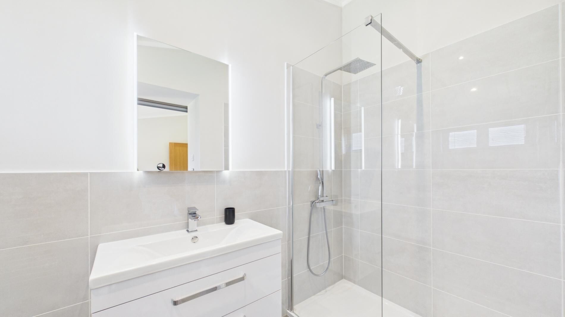 Une salle de bain moderne avec une douche à parois de verre, un meuble-lavabo blanc et un miroir.