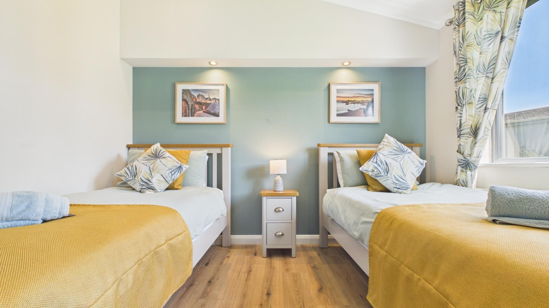 Une chambre double avec deux lits, une table de chevet et une fenêtre avec des rideaux.