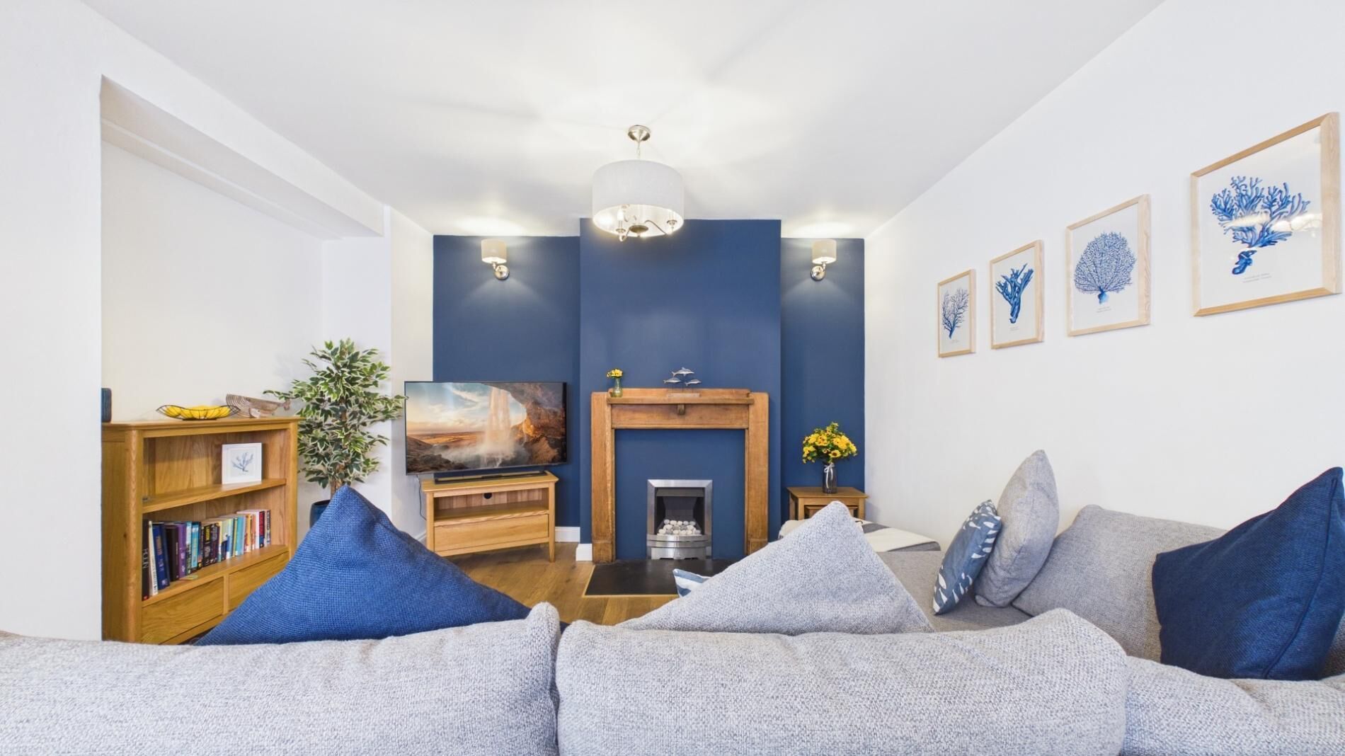 A living room with a fireplace, a bookshelf, a sofa, and wall art.