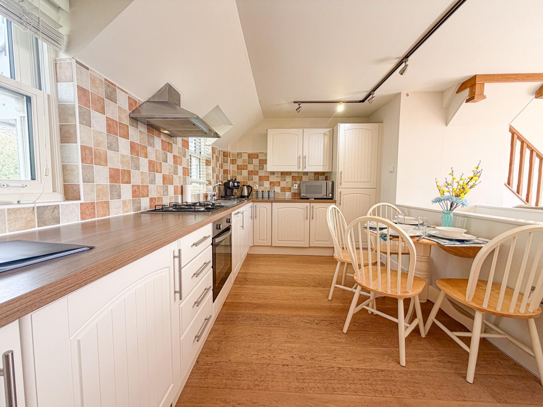 A kitchen with white cabinets, a wooden countertop, and a dining area with white chairs.