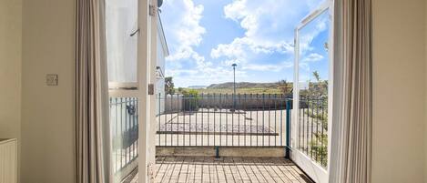 A room with a sliding glass door leading to an outdoor patio with a metal fence and a view of the countryside.