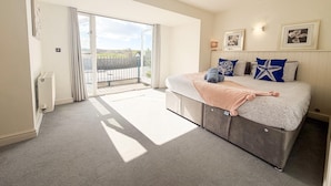 Un dormitorio con cama, balcón y vistas al exterior.