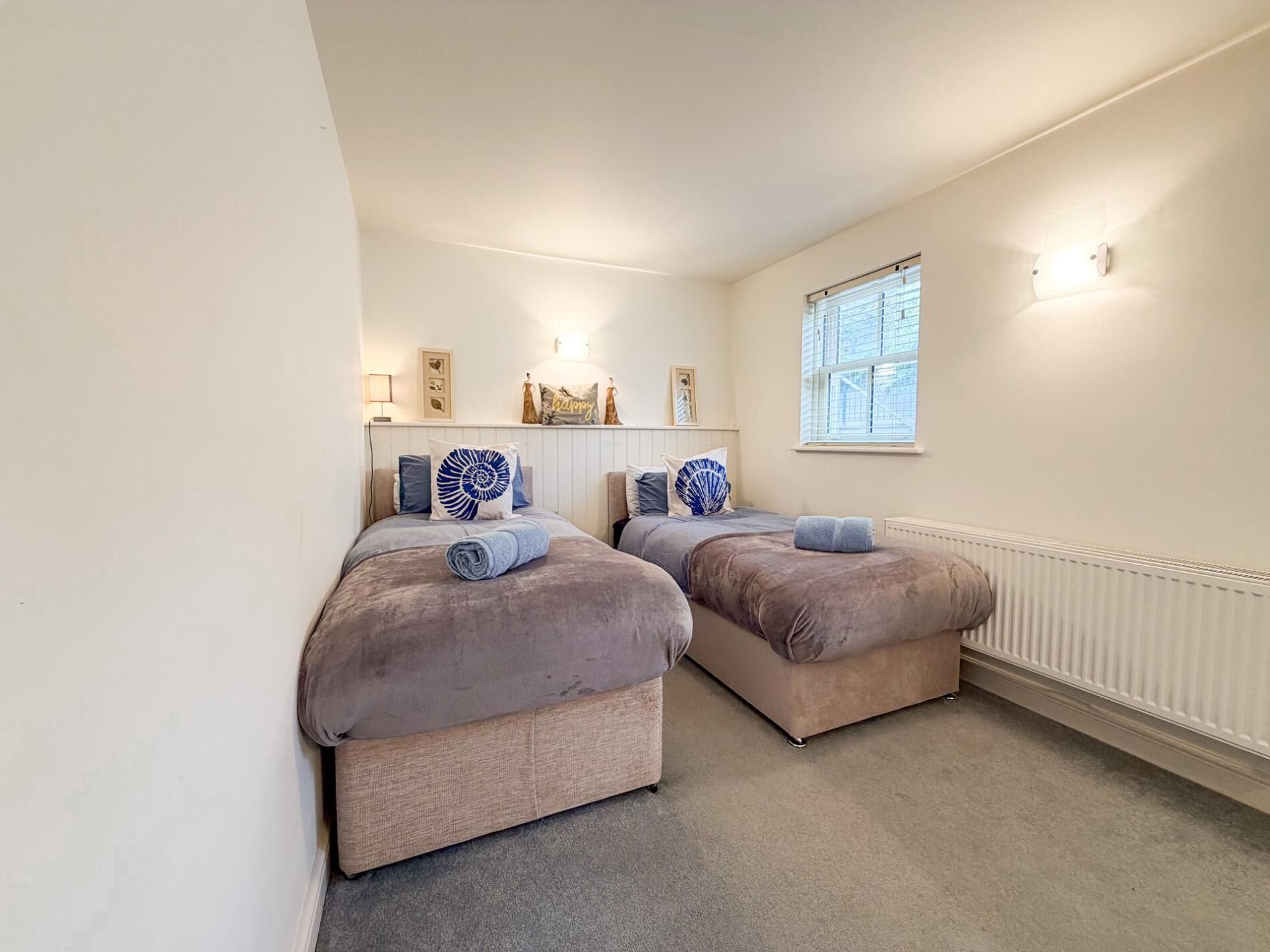 Une chambre avec deux lits, une fenêtre et un radiateur.