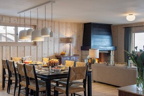 Ein Essbereich mit Holztisch, Korbstühlen und hängenden Pendelleuchten.