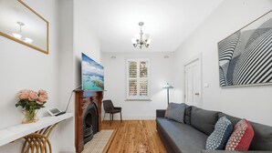 En moderne stue med pejs, sofa, spisebord og et stort vindue.