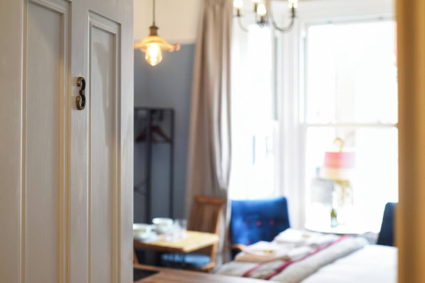 Una habitación de hotel con cama, una mesa y una lámpara colgante.