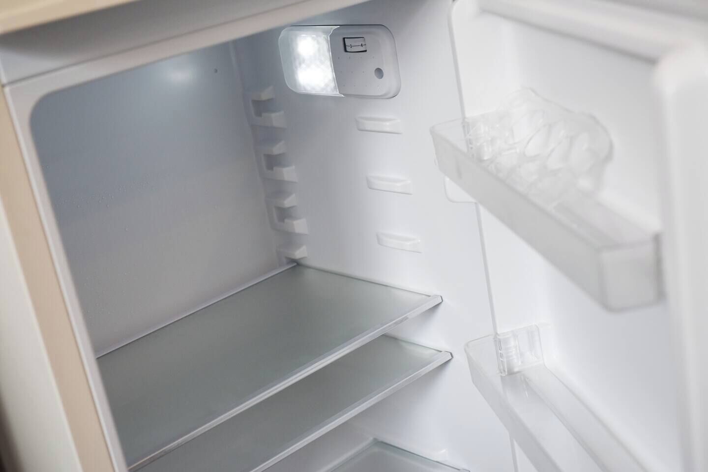 An empty refrigerator with shelves and a control panel.