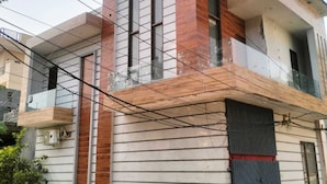 A modern two-story house with a balcony, a garage door, and visible power lines. - Vishal Homestay (Ajnala)